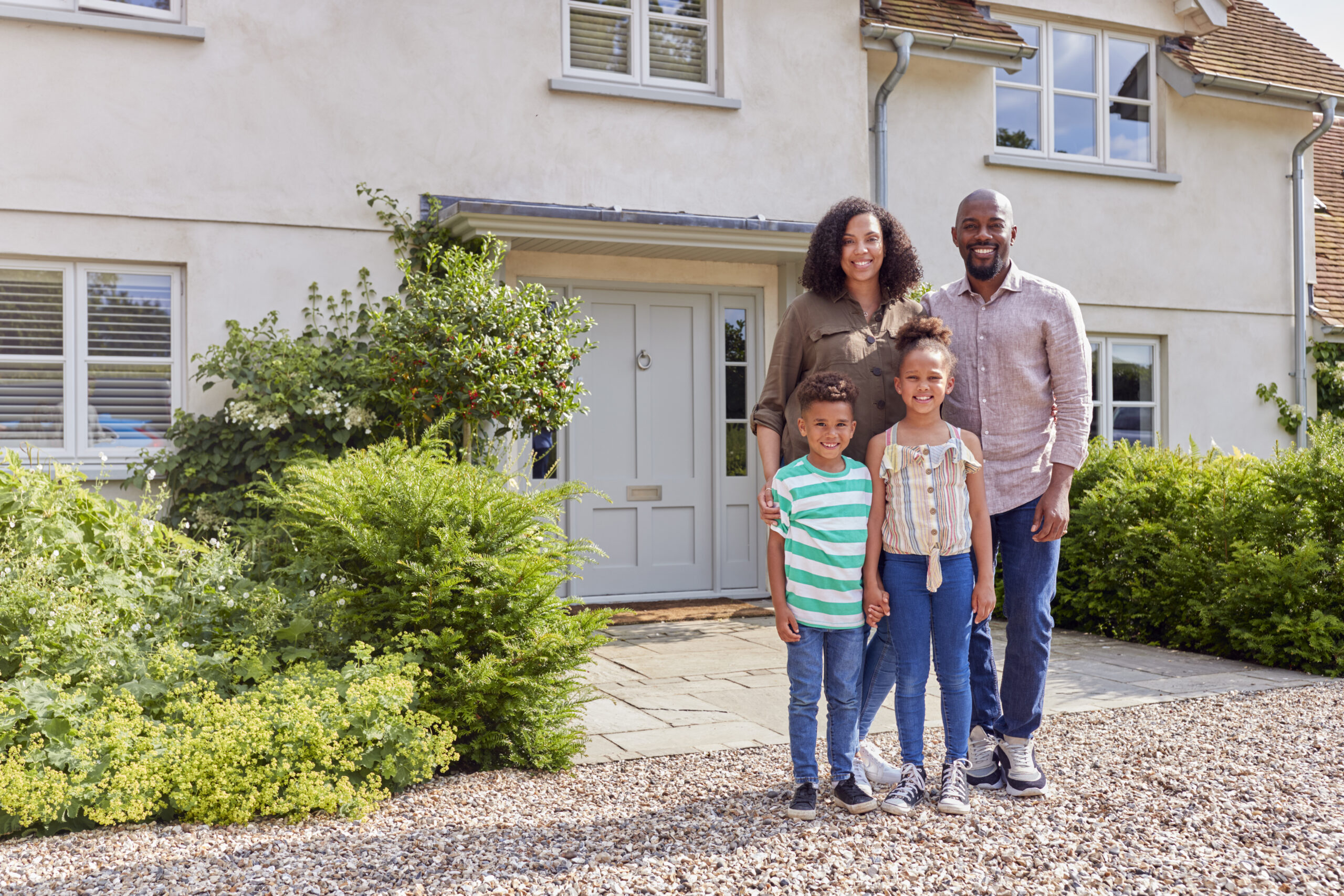 Portrait Of Smiling Family Standing Outside Home Together